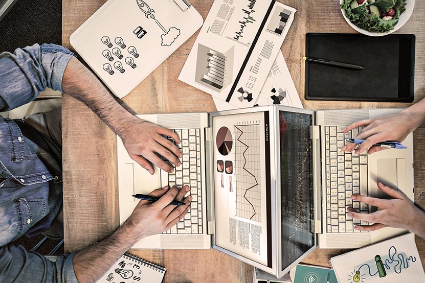 aerial view of a desk with two desktops and work material